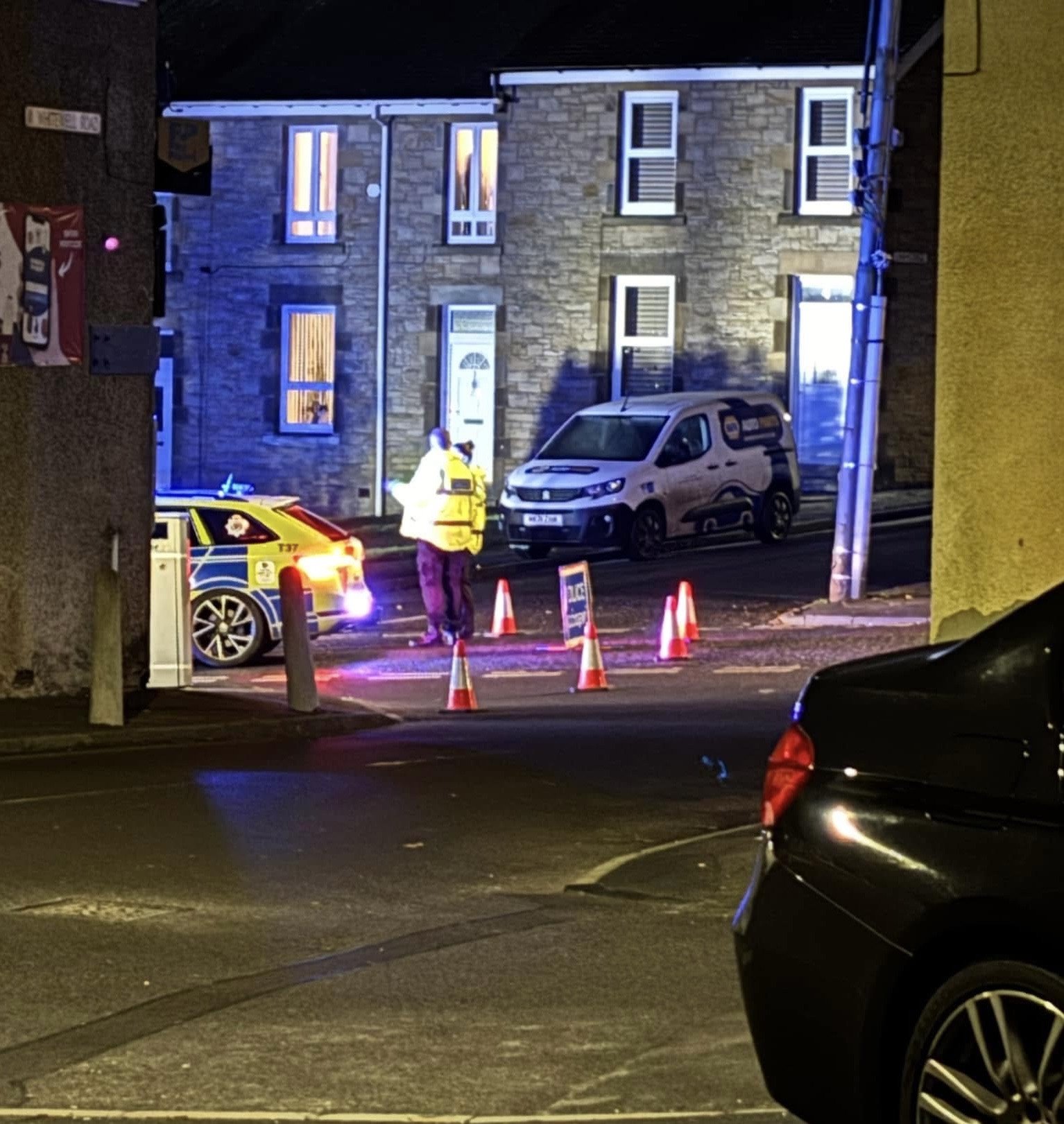 Photo of road closed with cones and police stood outside